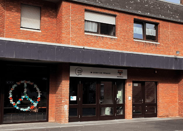 Backsteingebäude mit Eingang zum CVJM-Zentrum, dekoriertes Fenster mit Friedenszeichen.