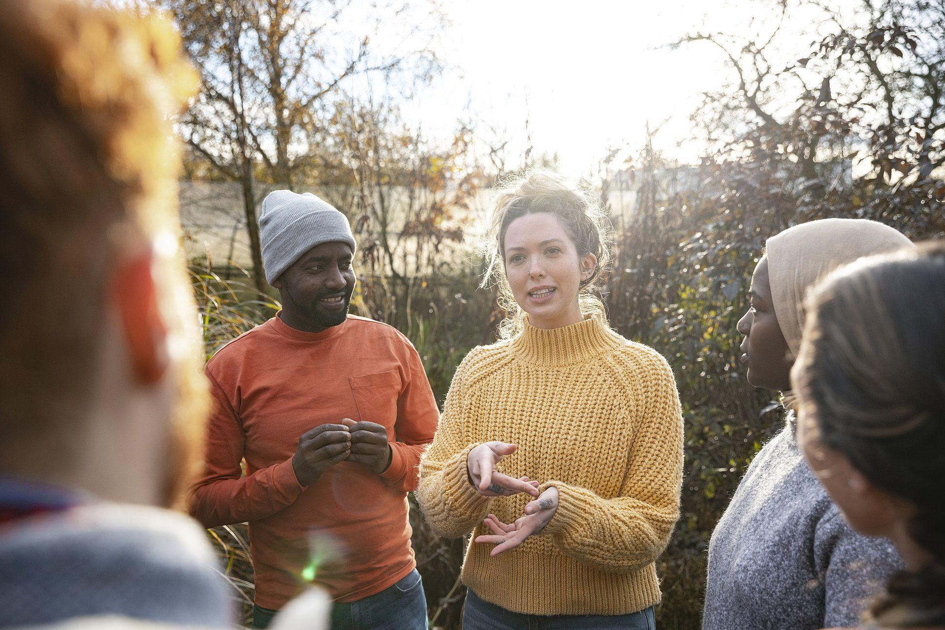 Eine Gruppe von Menschen steht im Freien und unterhält sich engagiert – ein Symbol für Gemeinschaft, Nachbarschaftshilfe und soziale Teilhabe.