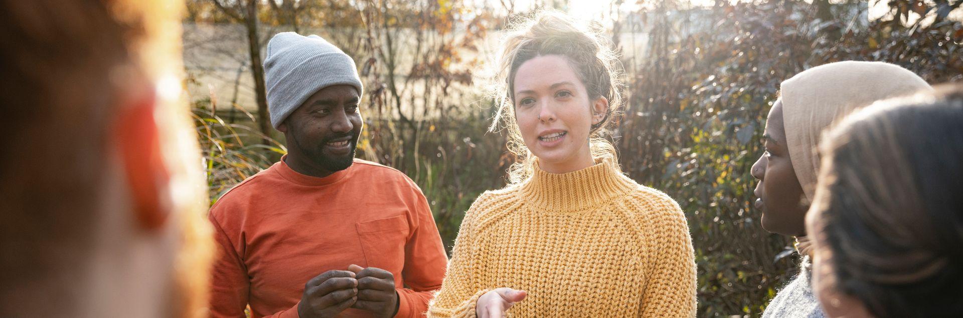 Menschen verschiedener Hautfarbe stehen im Kreis und unterhalten sich