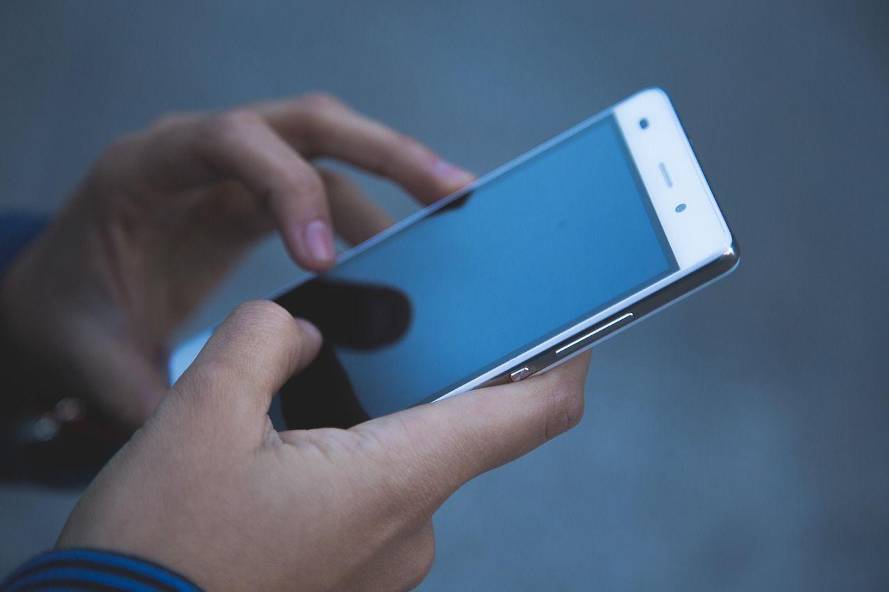 Eine Person hält ein Handy in beiden Händen. Eine Person hält ein Handy in beiden Händen.
